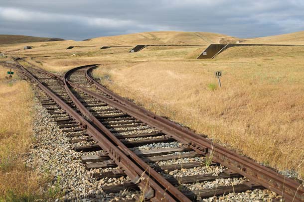 Railroad tracks through brown grass